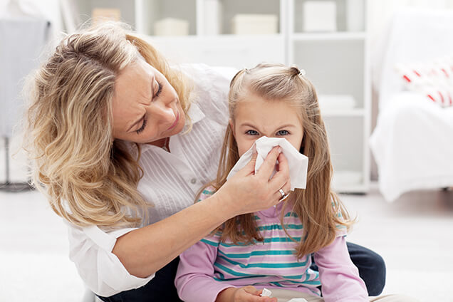 Mom helping her child blow her nose